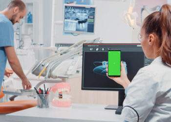 Patientin mit transparenten Alignern in der Hand vor weissem Hintergrund – Symbolbild für moderne Zahnmedizin
