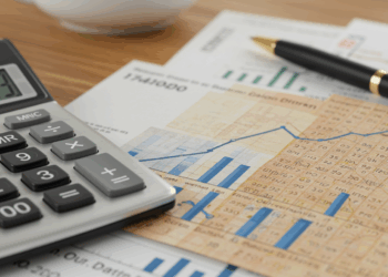 Schreibtisch mit Gehaltsabrechnung, Rechner und Diagramm mit ansteigender Linie zu Rentenbeiträgen.
